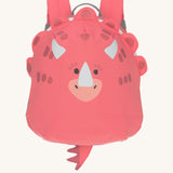 The Lassig tiny kids backpack in a bright coral pink, with a dinosaur face printed on and 3D embellishments and dino tail