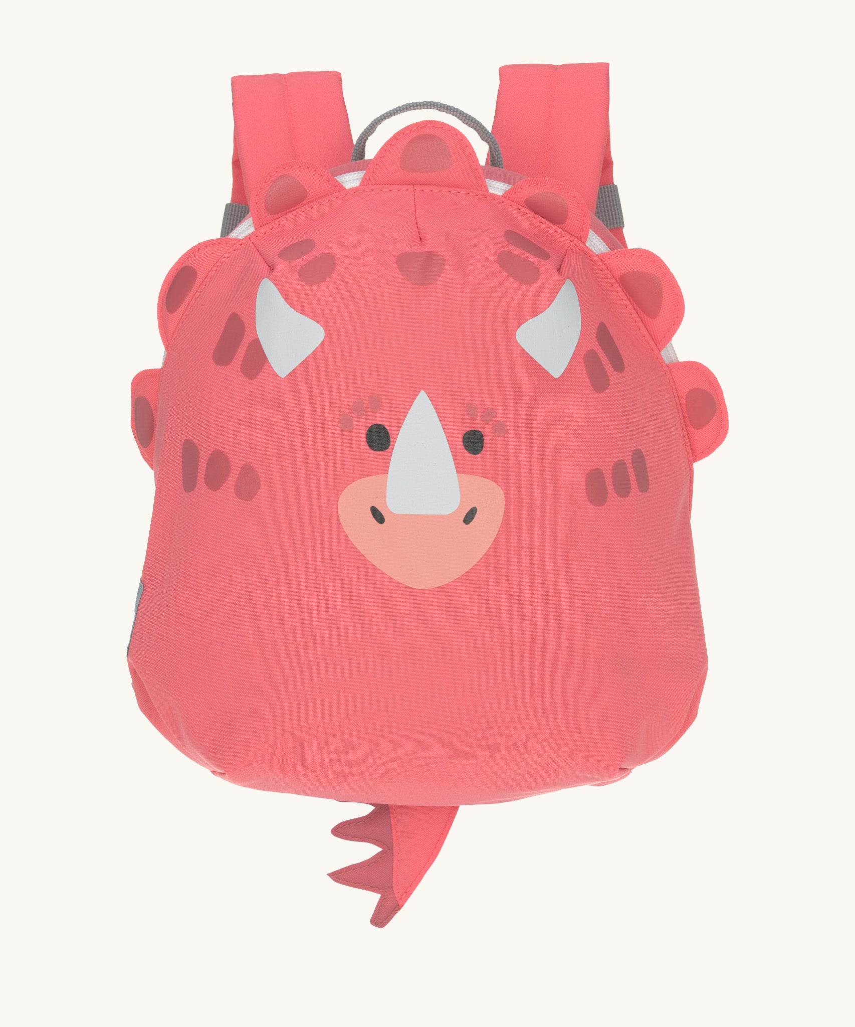 The Lassig tiny kids backpack in a bright coral pink, with a dinosaur face printed on and 3D embellishments and dino tail