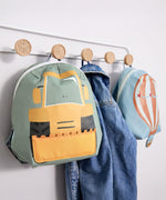 Lassig kids tiny backpack in digger and balloon design hanging from hooks with a denim jacket inbetween