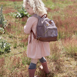 Little girl in a field wearing the Lassig dragonfly mini kids backpack.