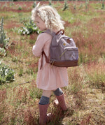 Little girl in a field wearing the Lassig dragonfly mini kids backpack.