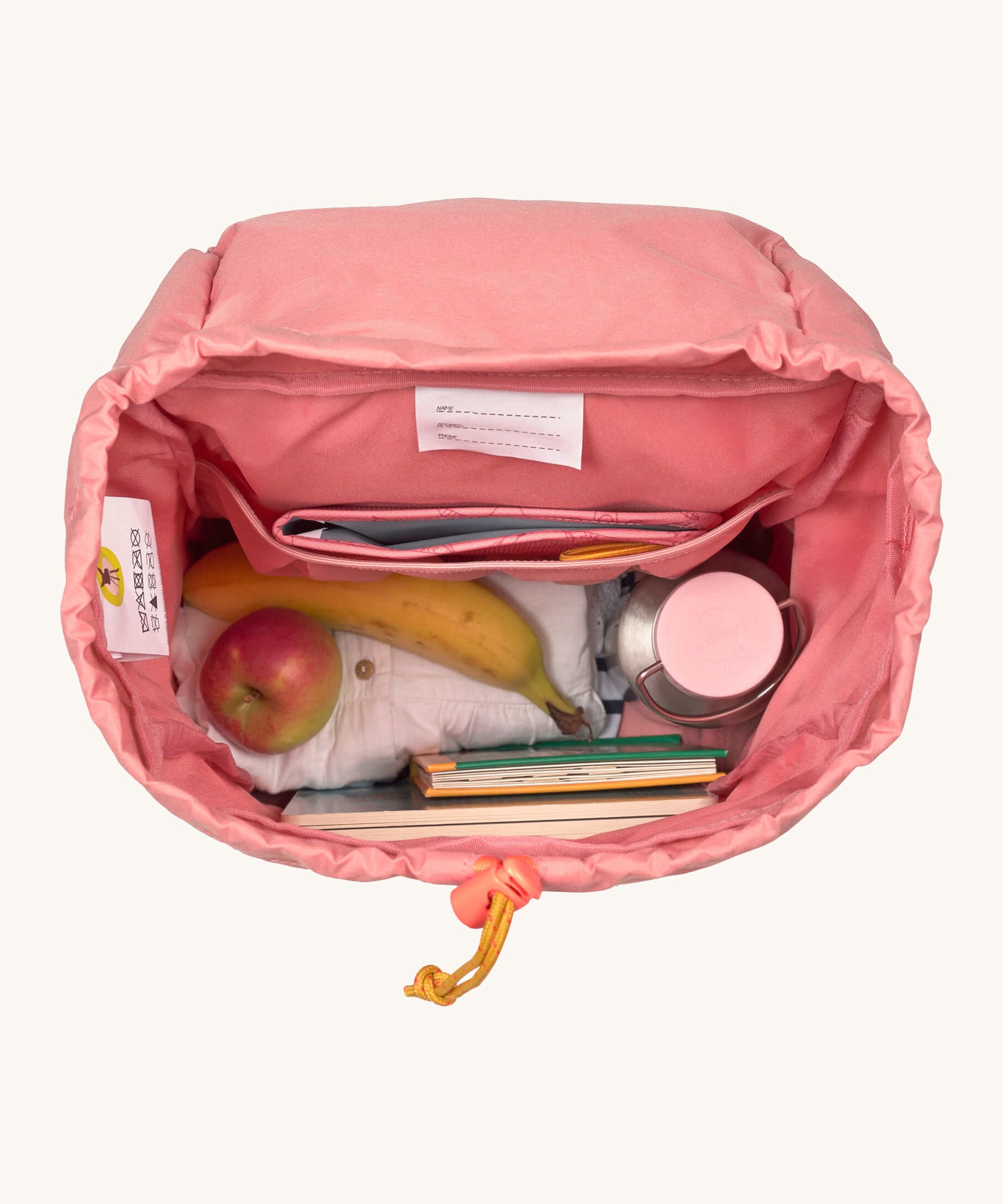 A close up of the Lassig kids mini adventure backpack in rose showing the space inside the main compartment and toggle detail for closing.