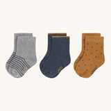 The Lassig 3 pack of organic cotton baby socks, one pair is grey with blue stripes, one is navy with mustard yellow trim on the cuffs, and one is mustard yellow with navy dots.