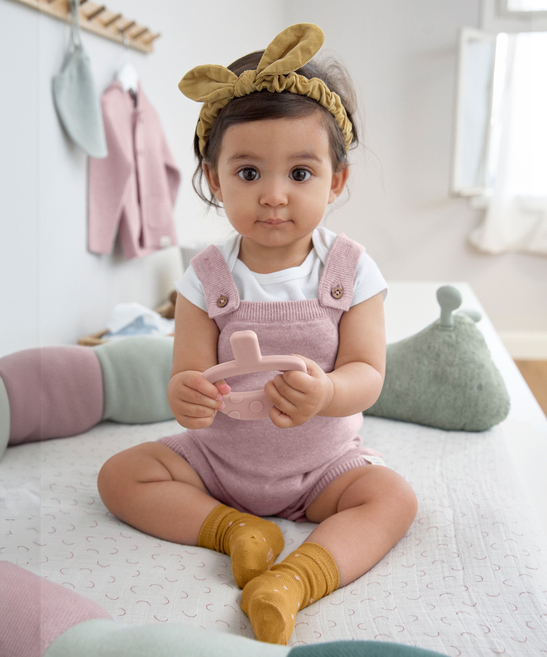 A baby sat down, wearing the Lassig organic cotton baby socks in mustard yellow with pink dots.
