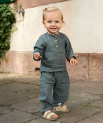 A toddler wearing a Lassig organic cotton muslin outfit in Petrol Green.