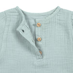 A closeup of the brown buttons on the Lassig organic cotton muslin long sleeved shirt for babies and toddlers, in a silver grey.