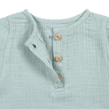 A closeup of the brown buttons on the Lassig organic cotton muslin long sleeved shirt for babies and toddlers, in a silver grey.