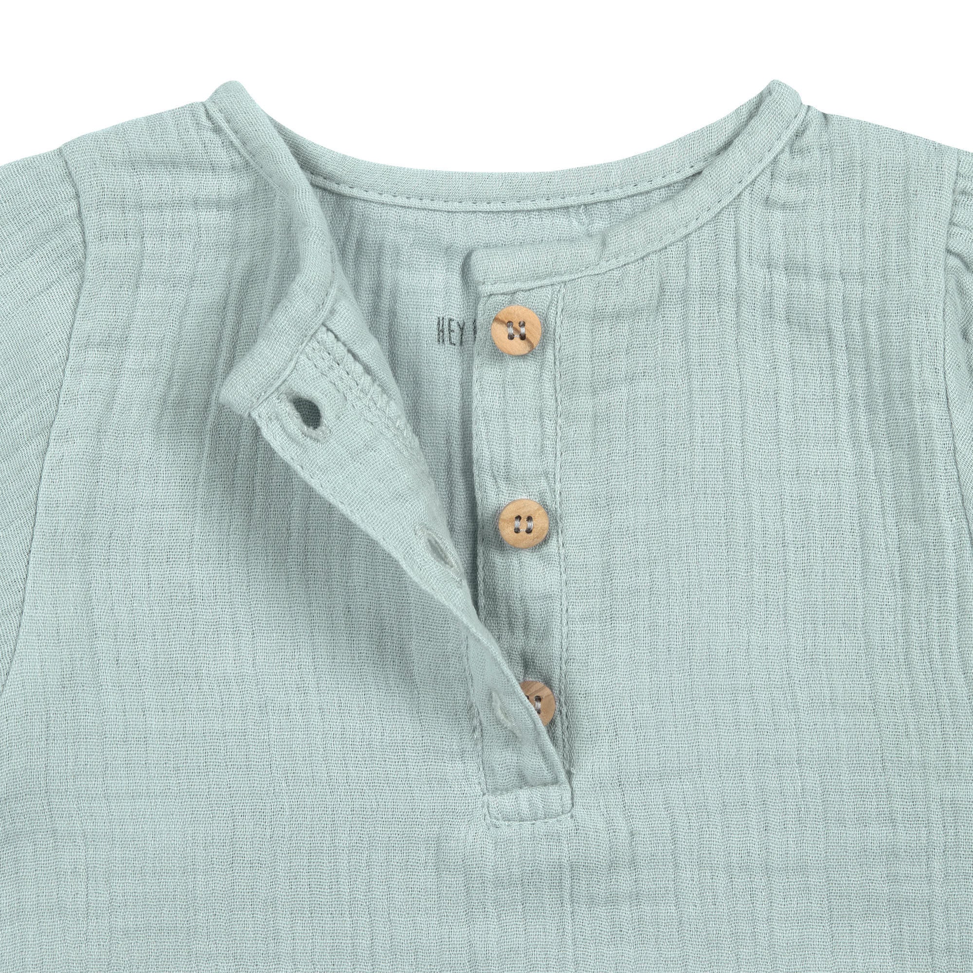 A closeup of the brown buttons on the Lassig organic cotton muslin long sleeved shirt for babies and toddlers, in a silver grey.