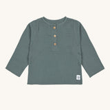 The Lassig organic cotton muslin long sleeved top for babies and toddlers, in a dark petrol green with little brown buttons.
