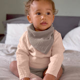 A baby wearing the Lassig organic cotton muslin long sleeved top, in a beautiful pale powder pink colour.
