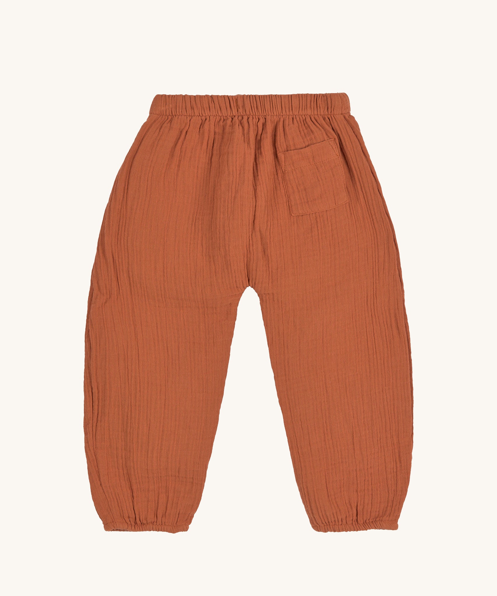 The back of the Lassig organic cotton muslin pants in an orange rust colour.