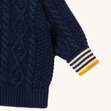 A close up of the Little Green Radicals navy aran knitted jumper available at Babipur. Showing the cable knit and the striped cuff detail on dark navy organic cotton fabric