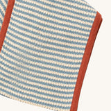A close up of the Little Green Radicals knitted scarf in blue stripes. showing the blue and cream stripes detail on organic cotton fabric
