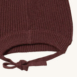 A close up of the Little Green Radicals chocolate knitted beanie hat showing the closed brown tie detail on  organic cotton fabric