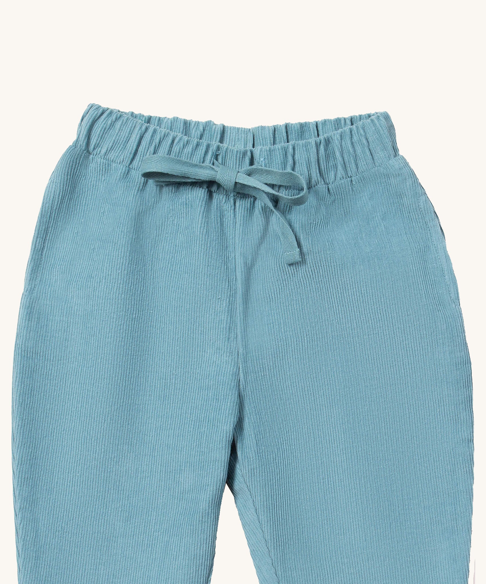 A close up of the Little Green Radicals comfy trousers in pale blue corduroy. Showing the corduroy detail and matching drawstring in pastel blue soft GOTS organic cotton fabric