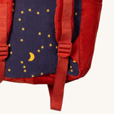 A close up of the Little Green Radicals ready for adventure backpack in dark night. Showing the red adjustable shoulder  strap detail and a close up of the starry night design on corduroy cotton fabric.