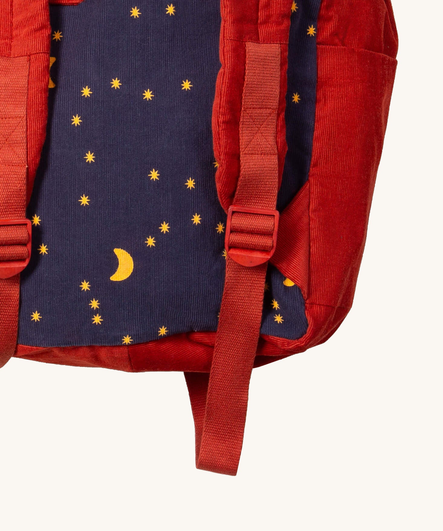 A close up of the Little Green Radicals ready for adventure backpack in dark night. Showing the red adjustable shoulder  strap detail and a close up of the starry night design on corduroy cotton fabric.