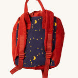 A close up of the Little Green Radicals ready for adventure backpack in dark night. Showing the red shoulder strap detail on navy and red corduroy cotton fabric.