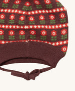 A close up of the Little Green Radicals flower collecting knitted beanie hat showing the closed dark orange tie detail on brown organic cotton fabric