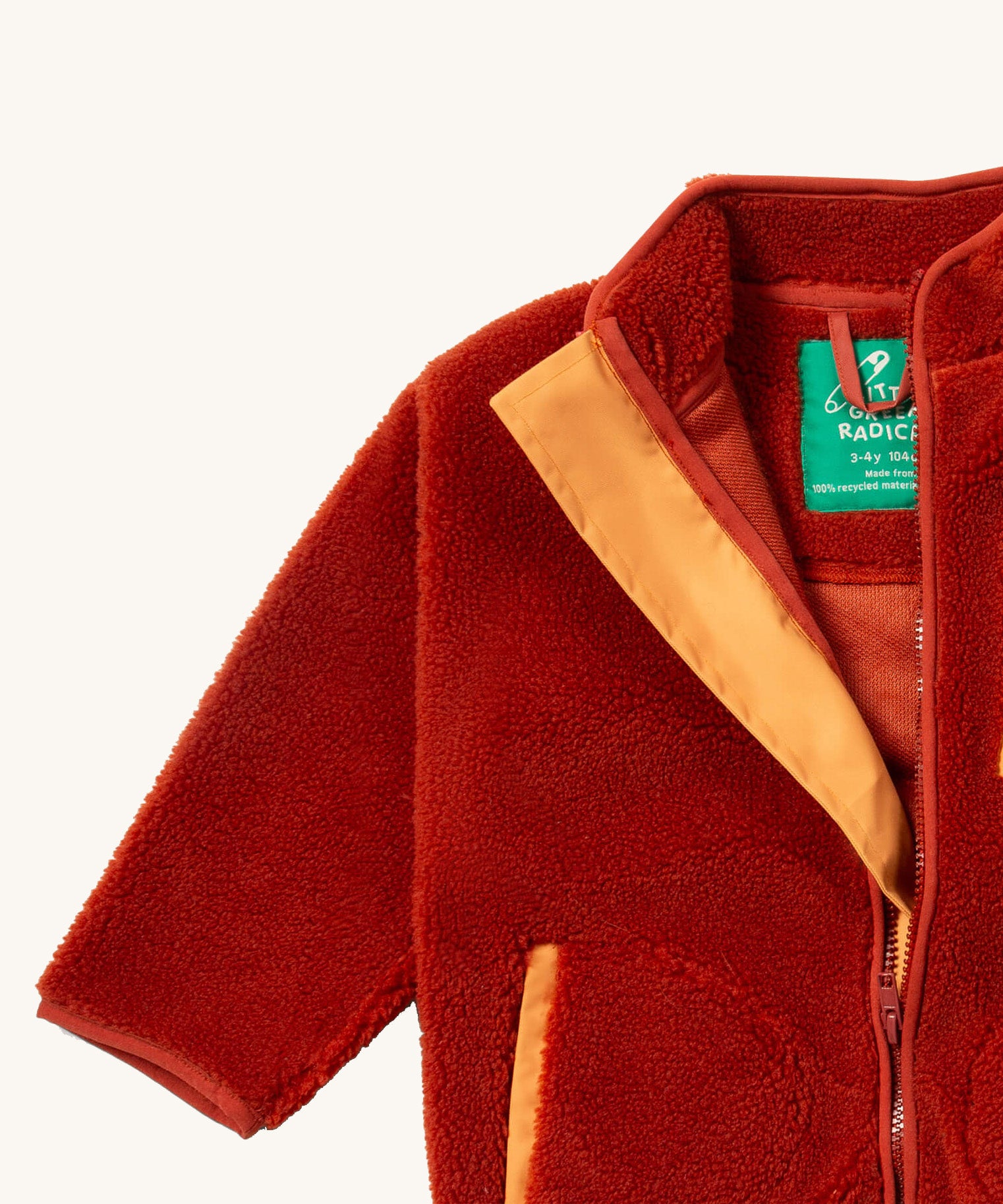 A close up of the Little Green Radicals zip up fleece jacket in ginger showing the full length zip detail with light orange trim on dark orange fleece fabric.