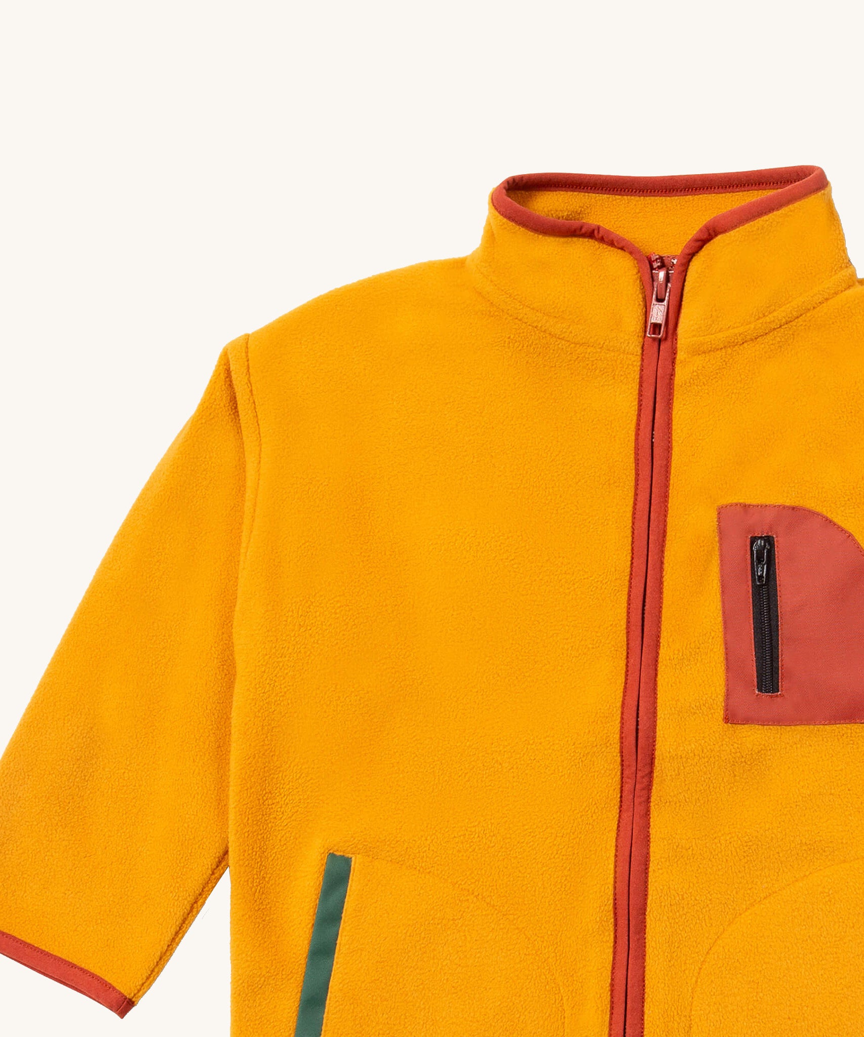 A close up of the Little Green Radicals polar fleece jacket in gold showing the red trim and full length zip detail on dark yellow recycled polyester fabric.
