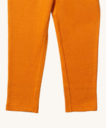 A close up of the Little Green Radicals golden waffle leggings showing the leg cuff detail and the waffle texture on yellow organic cotton fabric.