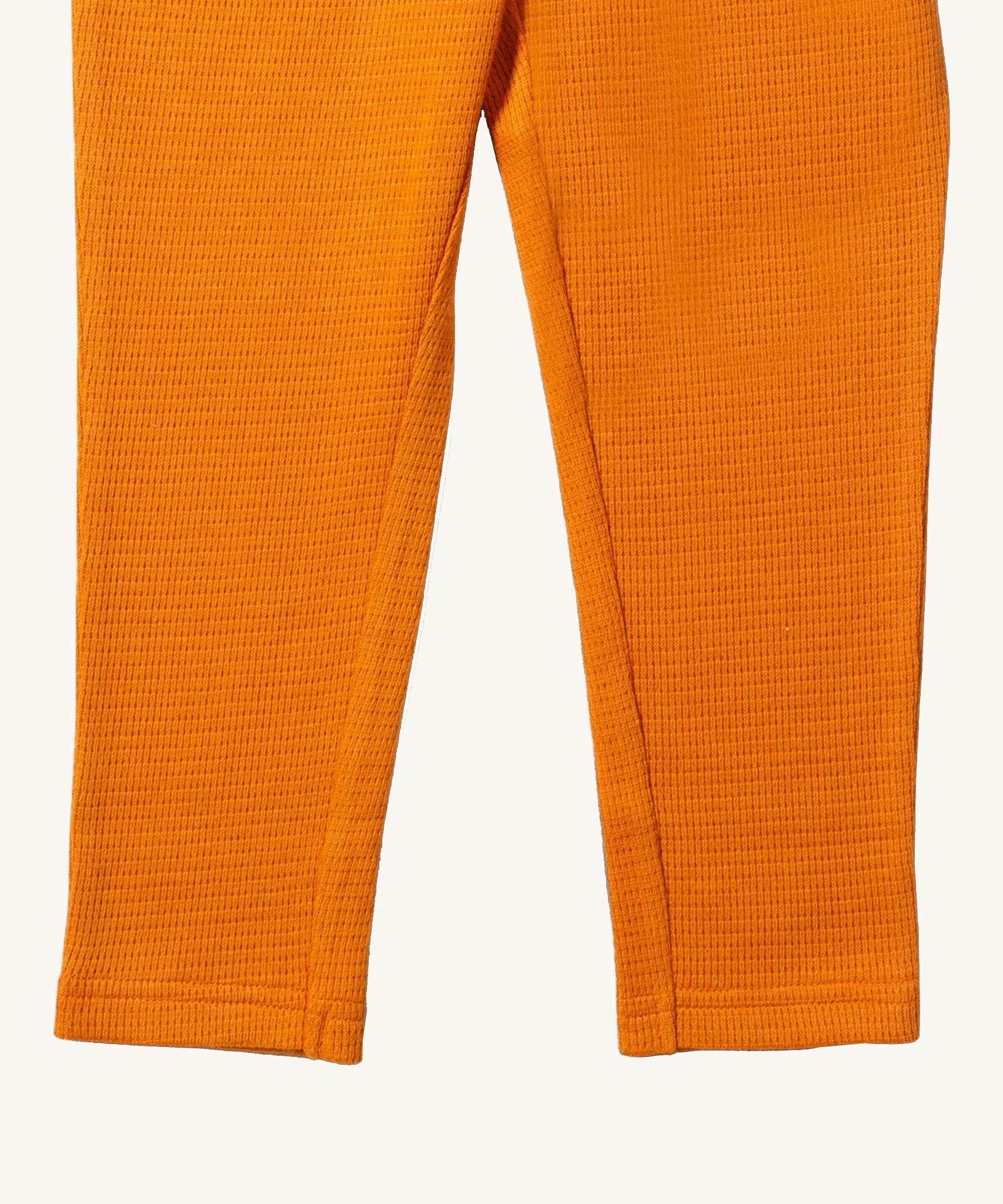 A close up of the Little Green Radicals golden waffle leggings showing the leg cuff detail and the waffle texture on yellow organic cotton fabric.