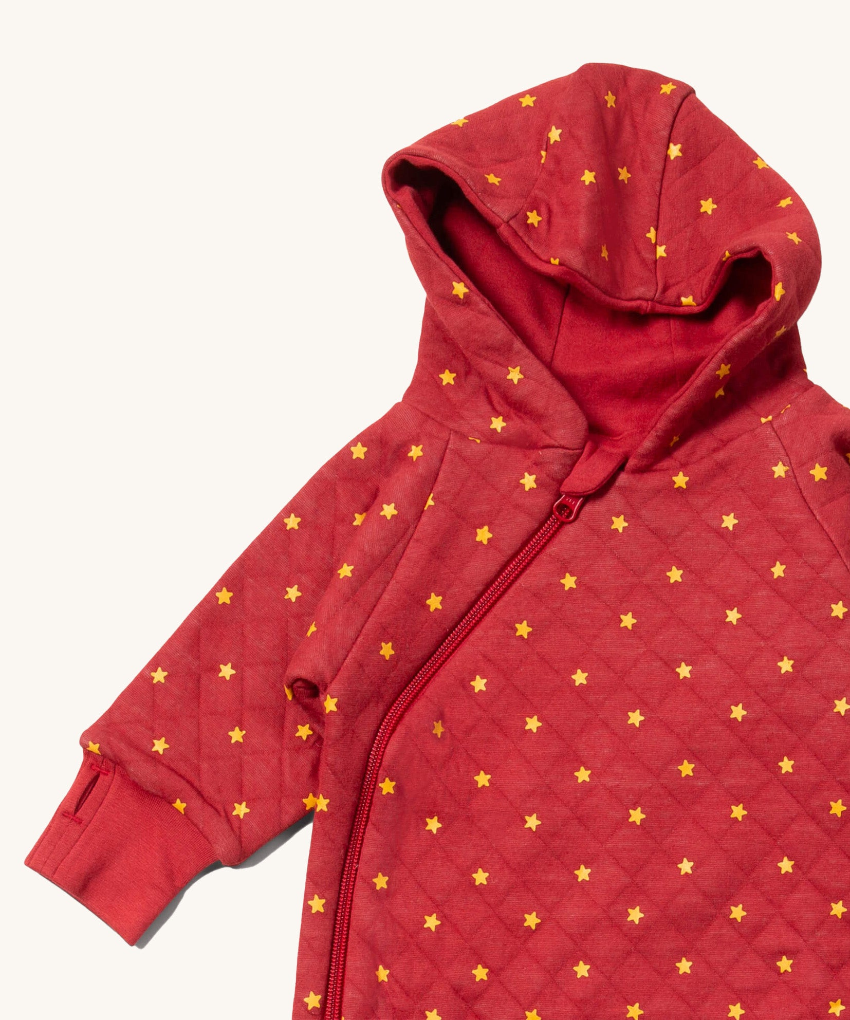 A close up of the Little Green Radicals hooded snug suit in red stars showing the hood and zip detail on GOTS organic cotton fabric