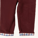 A close up of the Little Green Radicals jeans in chocolate corduroy. Showing the corduroy detail  and check design inner on dark maroon organic cotton fabric