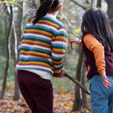 2 children playing with sticks in woodland wearing the Little Green Radicals comfy trousers in a corduroy style made from GOTS organic cotton.