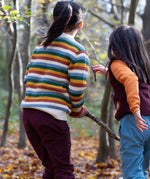 2 children playing with sticks in woodland wearing the Little Green Radicals comfy trousers in a corduroy style made from GOTS organic cotton.