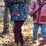 Children playing in the woods and wearing the chocolate comfy and pale blue trousers. A corduroy style trouser made from GOTS organic cotton fabric.