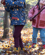 Children playing in the woods and wearing the chocolate comfy and pale blue trousers. A corduroy style trouser made from GOTS organic cotton fabric.