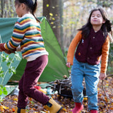 Children playing in the woods and wearing the chocolate comfy and pale blue trousers. A corduroy style trouser and features a drawstring for easy size adjsuting  made from GOTS organic cotton fabric.