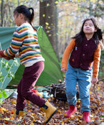 Children playing in the woods and wearing the chocolate comfy and pale blue trousers. A corduroy style trouser and features a drawstring for easy size adjsuting  made from GOTS organic cotton fabric.