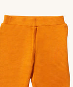 A close up of the Little Green Radicals golden waffle leggings showing the elasticated waistband detail and the waffle texture on yellow organic cotton fabric.