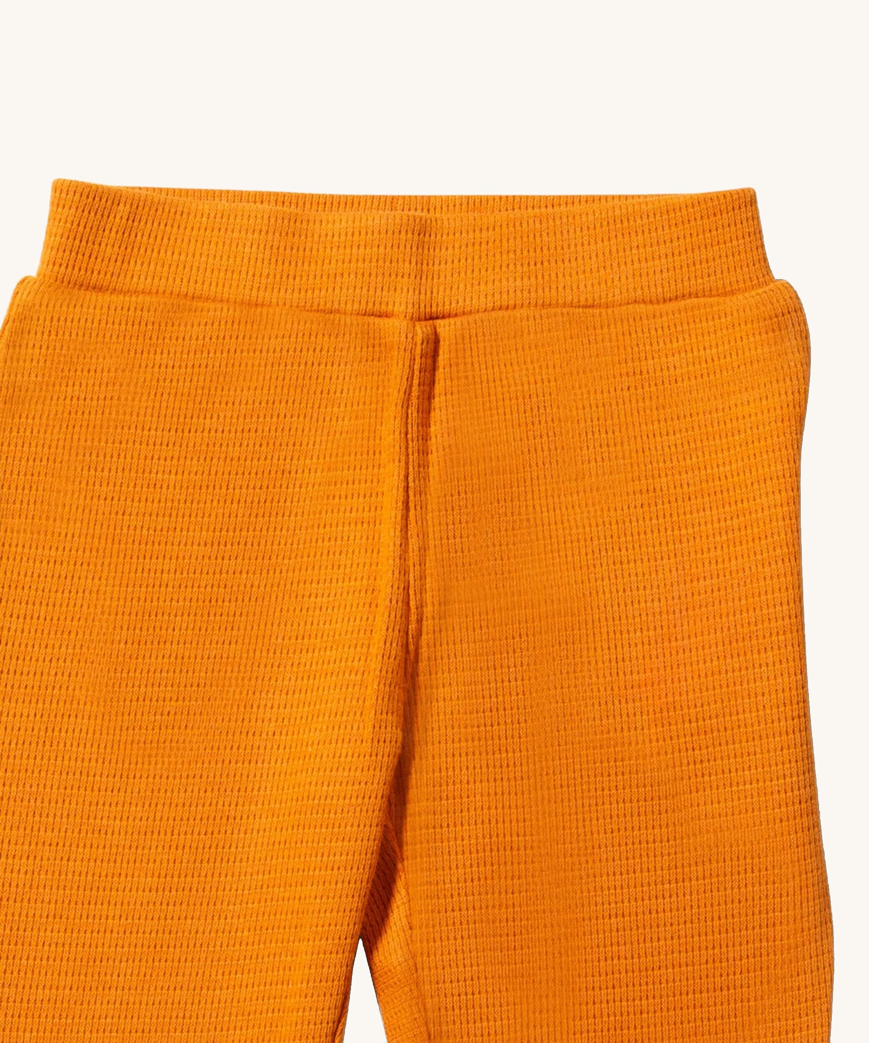 A close up of the Little Green Radicals golden waffle leggings showing the elasticated waistband detail and the waffle texture on yellow organic cotton fabric.