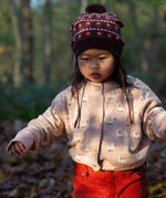 A child wearing the soft pink Little Green Radicals knitted cardigan in puddle ducks outside. Showing the button fasteners and a close up of the white ducks