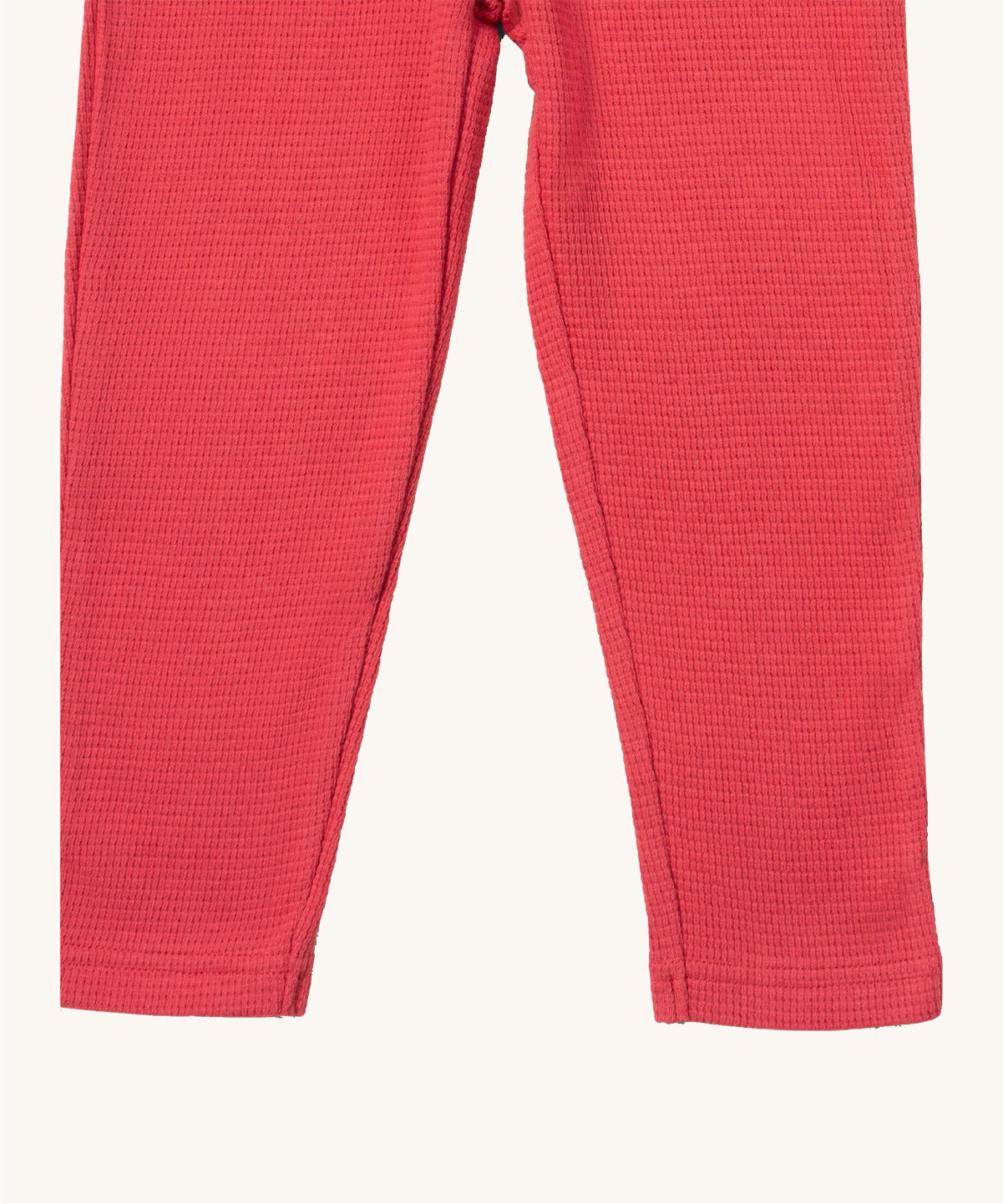 A close up of the Little Green Radicals pink berry waffle leggings showing the waffle knit and leg cuff detail on pink organic cotton fabric