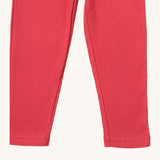 A close up of the Little Green Radicals pink berry waffle leggings showing the waffle knit and leg cuff detail on pink organic cotton fabric
