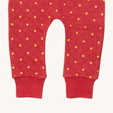 A close up of the Little Green Radicals red star quilted joggers. Showing the quilted stitch and elasticated leg cuff detail on red organic cotton fabric.