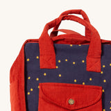 A close up of the Little Green Radicals ready for adventure backpack in dark night. Showing the handle and front pocket detail on navy and red corduroy cotton fabric.
