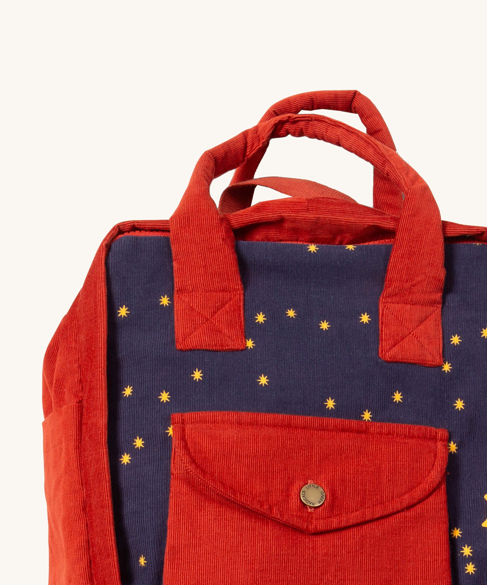 A close up of the Little Green Radicals ready for adventure backpack in dark night. Showing the handle and front pocket detail on navy and red corduroy cotton fabric.