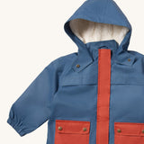 A close up of the Little Green Radicals waterproof coat in moonlight blue Showing the sherpa fleece liner, the full length zip and 2 side pockets in red trim detail on blue recycled polyester fabric