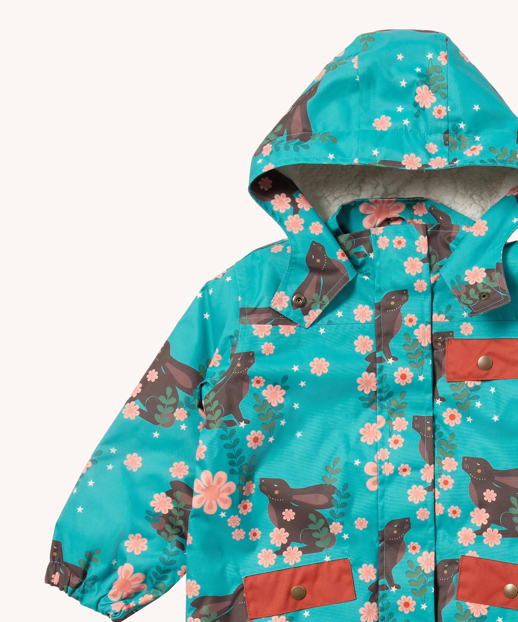 A close up of the Little Green Radicals waterproof adventure coat in winter rabbits showing the sherpa fleece liner under the hood, the full length zip and 2 side pockets in red trim detail on turquoise recycled polyester fabric