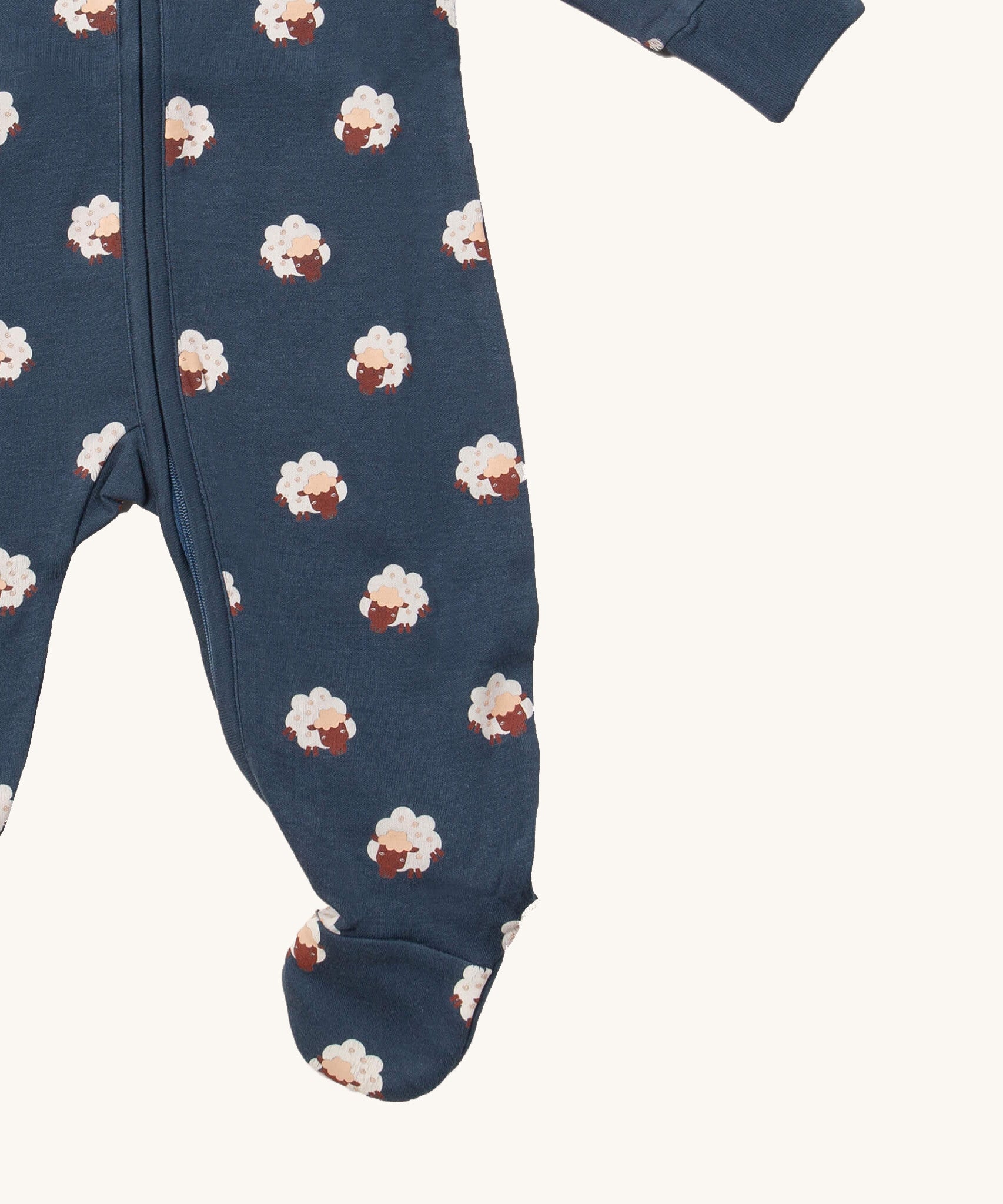 A close up of the Little Green Radicals navy sheep  baby grow, showing the zipper fastener detail and built in feet feature