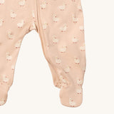 A close up of the Little Green Radicals turquoise rainbow baby grow, showing the zip detail around the crotch on light pink organic cotton fabric with cute duck prints.