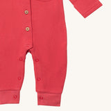 A close up of the Little Green Radicals pink waffle playsuit showing the button fastener detail and poppers around the crotch.