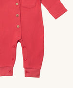 A close up of the Little Green Radicals pink waffle playsuit showing the button fastener detail and poppers around the crotch.