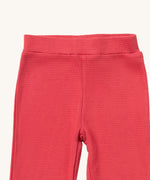 A close up of the Little Green Radicals pink berry waffle leggings showing the waffle knit detail and elasticated waist band on pink organic cotton fabric